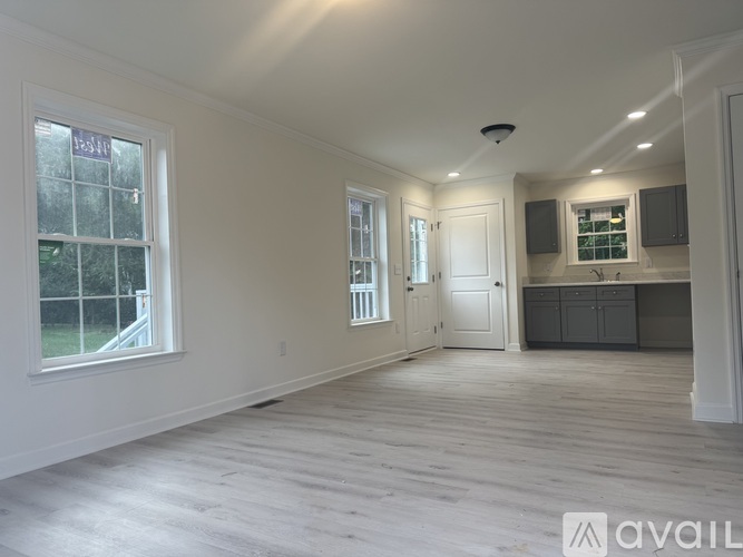 A spacious room with wooden flooring and white walls.
