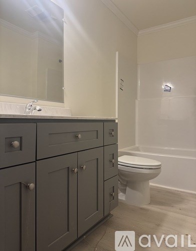 A bathroom with a toilet, sink, and cabinets.