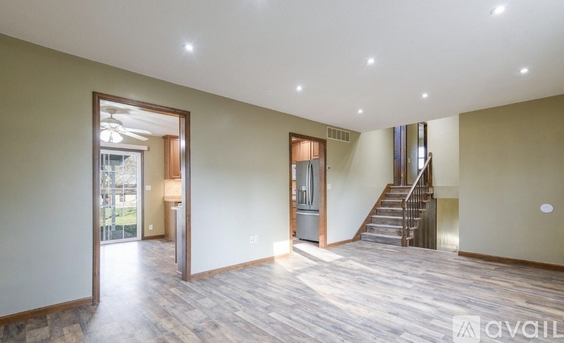 A spacious room with wooden flooring and a staircase leading to another level.