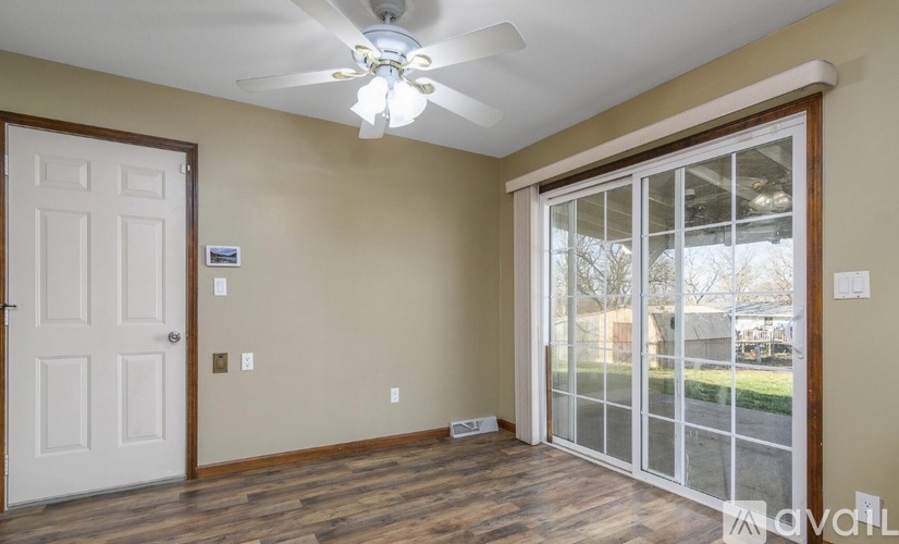 A room with a ceiling fan and sliding glass doors.