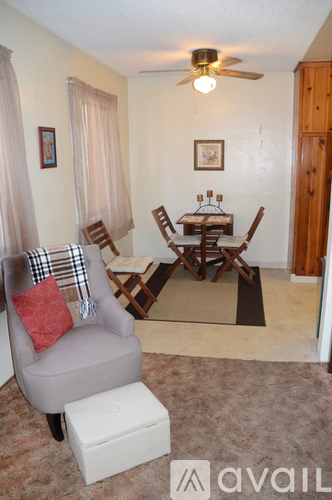 A living room with a grey armchair and a small table with chairs.