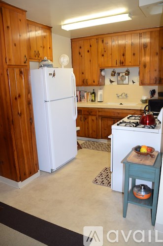 A kitchen with a white refrigerator and a blue stool.