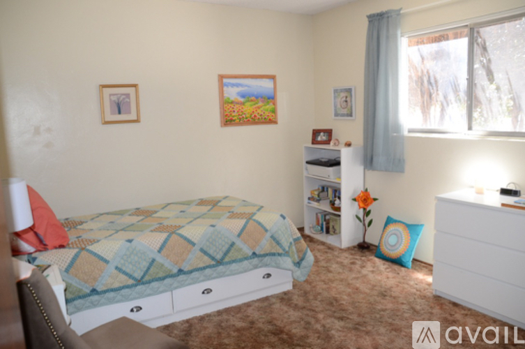 A bedroom with a bed, dresser, and a window with a view of trees outside.