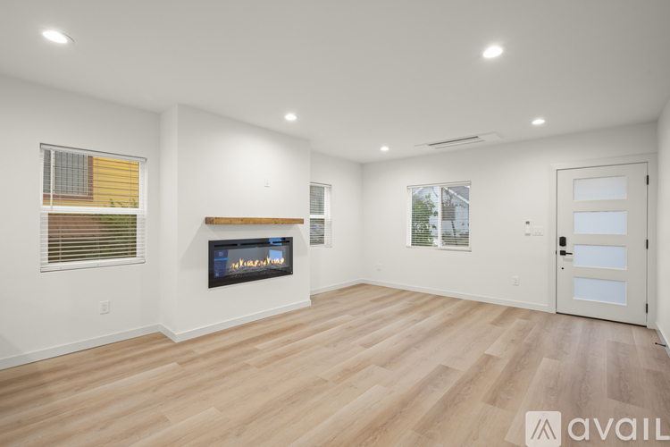 A spacious room with a fireplace and wooden flooring.