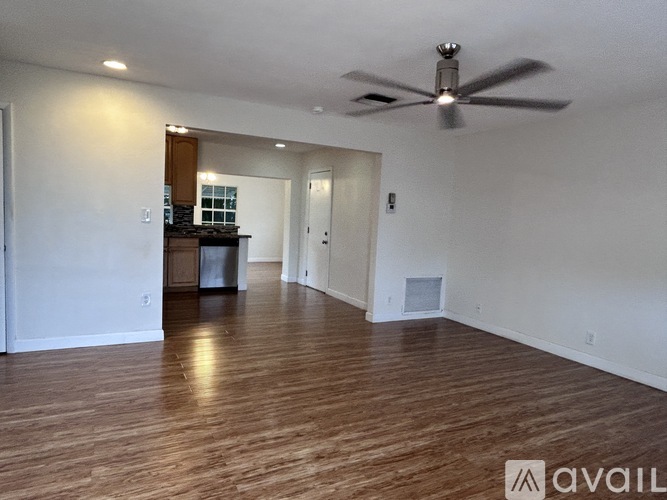 A spacious room with a ceiling fan and wooden flooring.