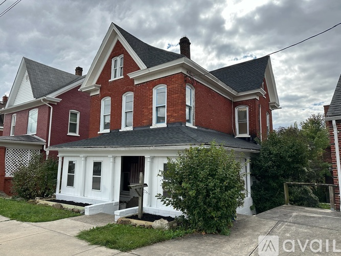 A red brick house with a white porch.
