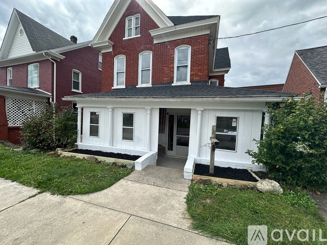 A red brick house with a white porch.