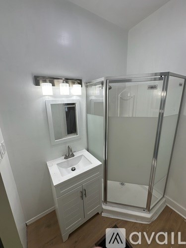 A bathroom with a sink, mirror, and shower.