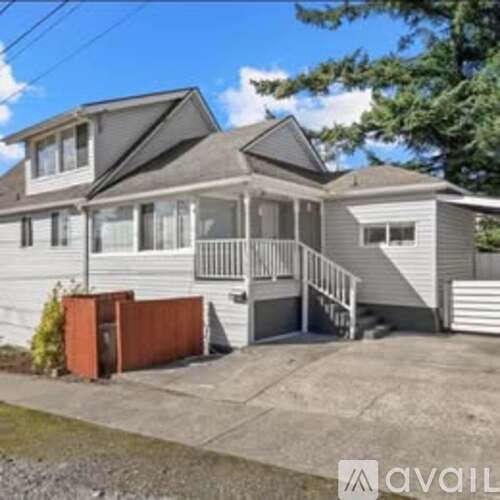 A two-story house with a grey exterior and a brown fence.