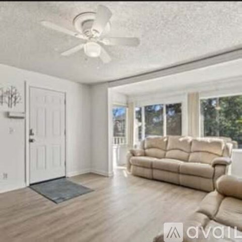 A living room with a beige sofa and a ceiling fan.