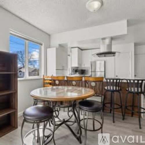 A kitchen with a table and chairs in the foreground and a window showing a snowy landscape outside.