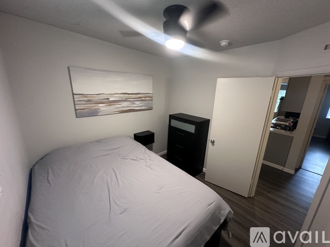A bedroom with a bed, a ceiling fan, and a painting on the wall.