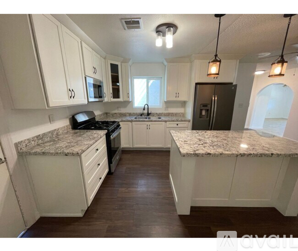 A kitchen with white cabinets and granite countertops.