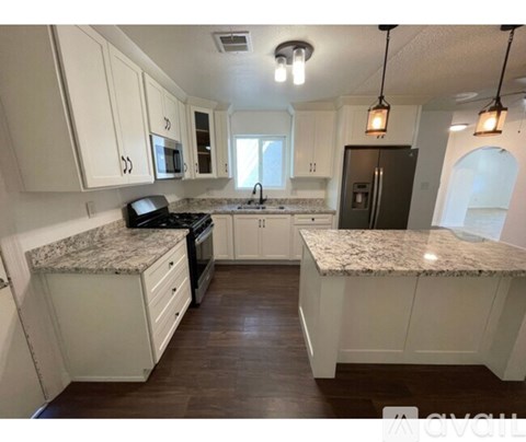 A kitchen with white cabinets and granite countertops.