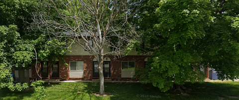 A tree stands in front of a red brick building.