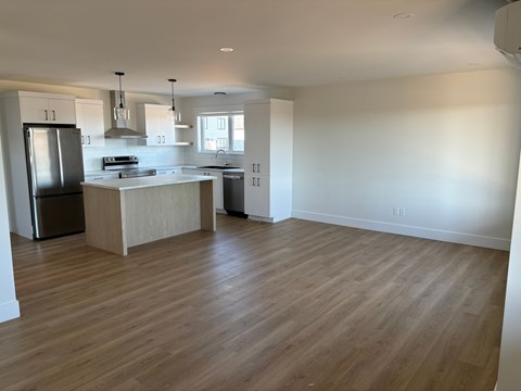 A kitchen with a refrigerator, sink, and stove.