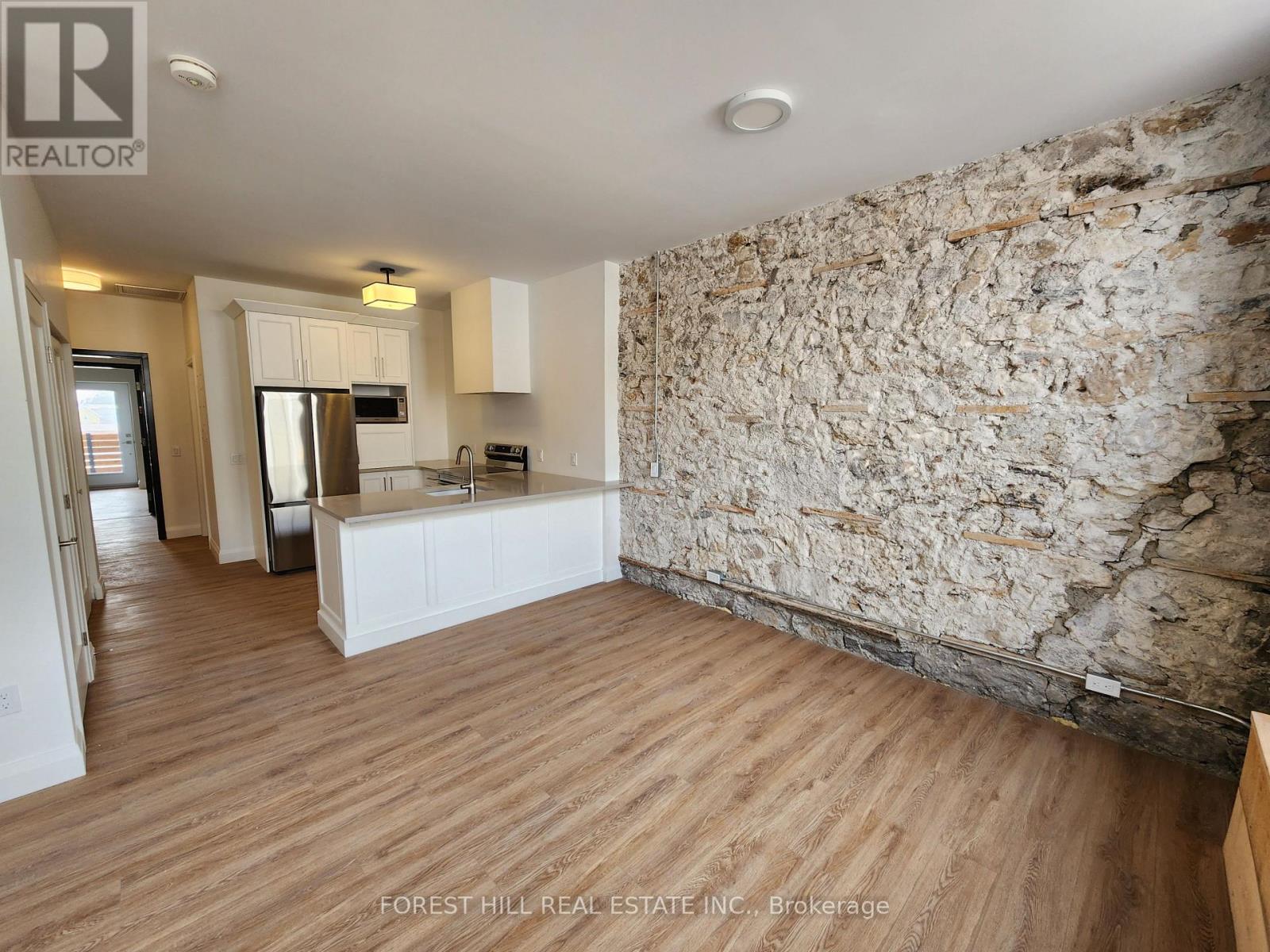 A kitchen area with wooden floors and a stone wall.