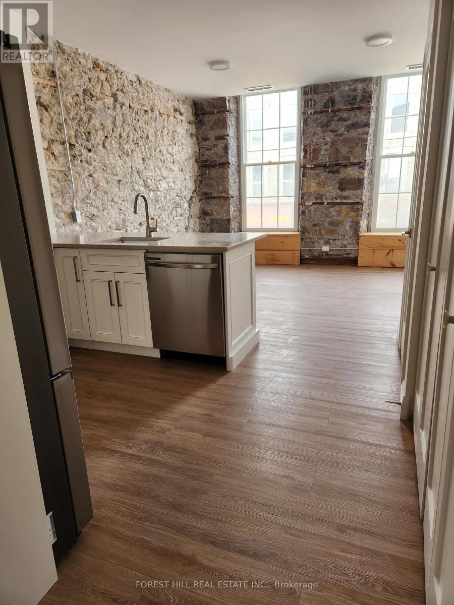 A kitchen with a stone wall and wooden floors.