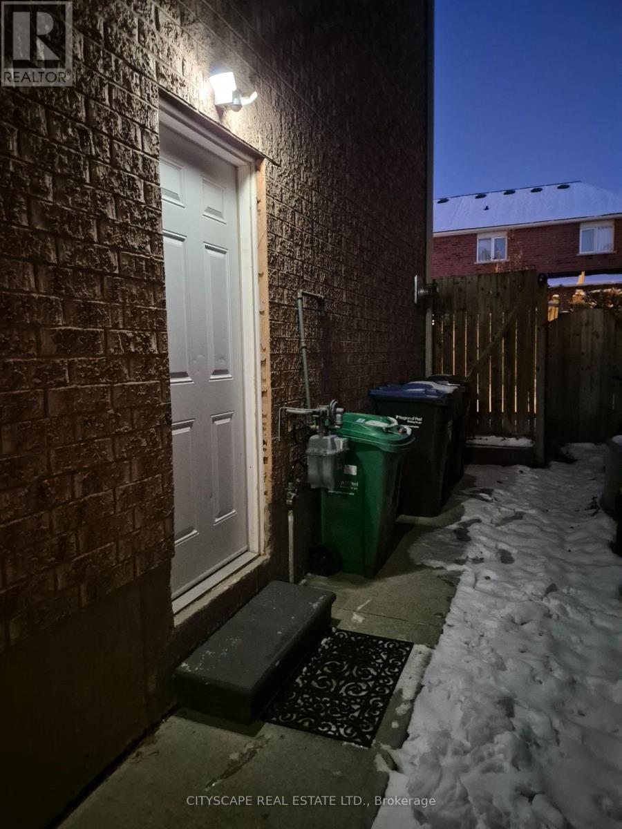 A snowy night scene with a white door and a green bin.