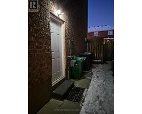 A snowy night scene with a white door and a green bin.