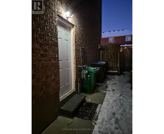 A snowy night scene with a white door and a green bin.