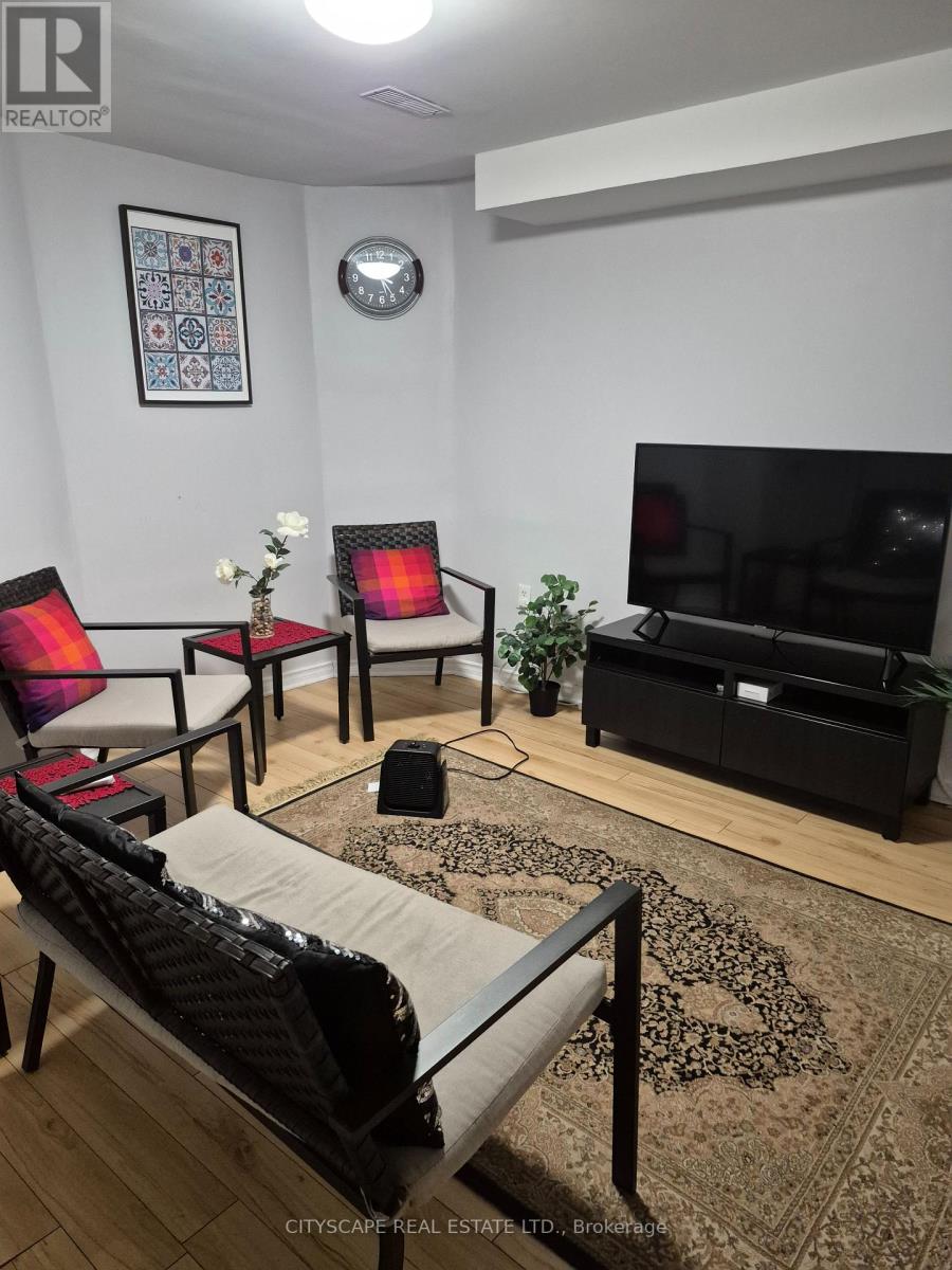 A living room with a sofa, chairs, and a television.