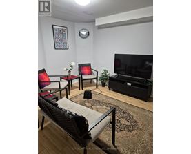 A living room with a sofa, chairs, and a television.