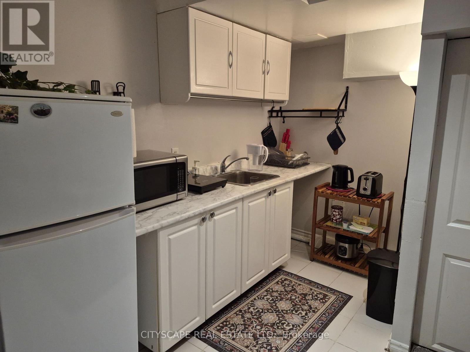 A kitchen with white cabinets and a white fridge.
