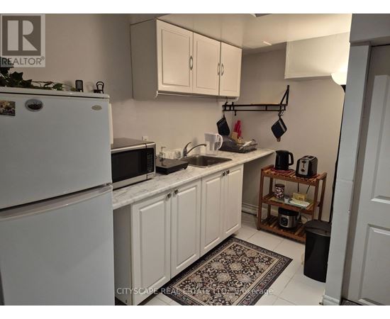 A kitchen with white cabinets and a white fridge.