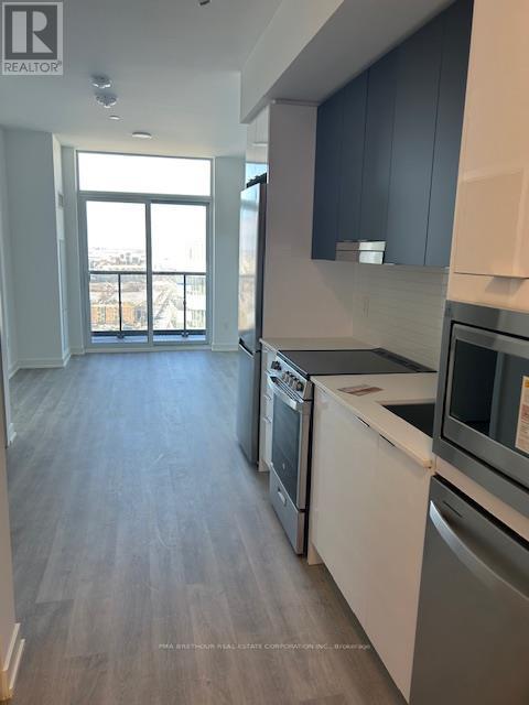 A modern kitchen with stainless steel appliances and wooden flooring.