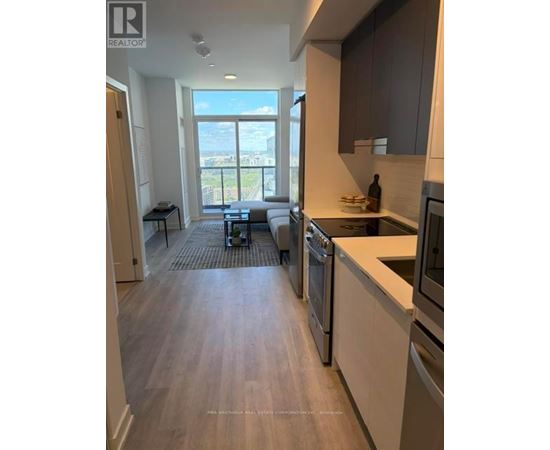 A modern kitchen with stainless steel appliances and wooden flooring.