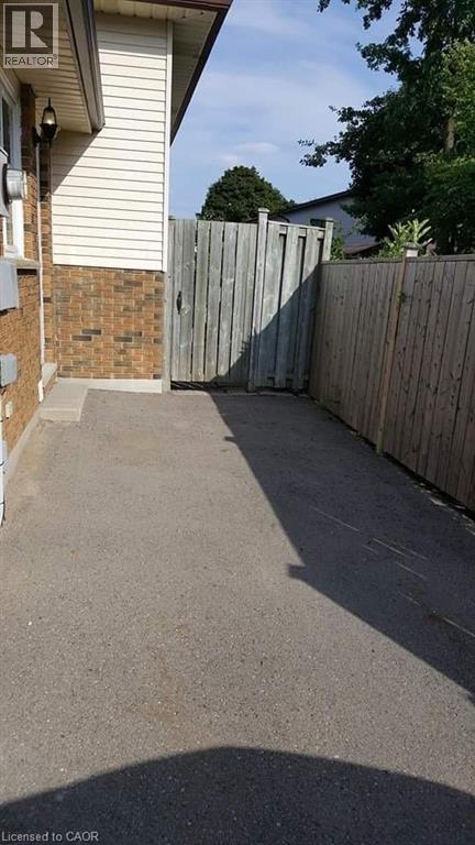 A concrete driveway leads to a house with a wooden fence.