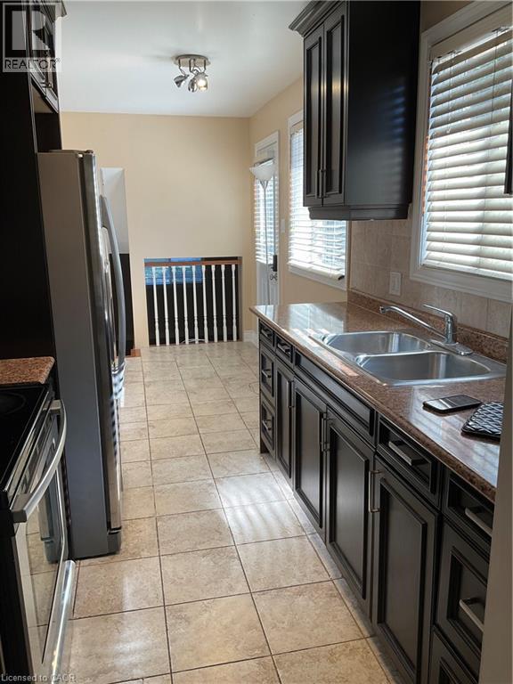 A kitchen with black cabinets and a refrigerator.