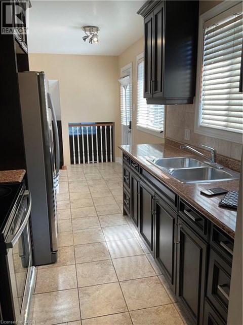 A kitchen with black cabinets and a refrigerator.