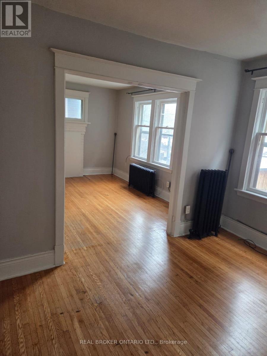 A room with wooden floors and a window with black curtains.
