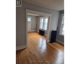 A room with wooden floors and a window with black curtains.