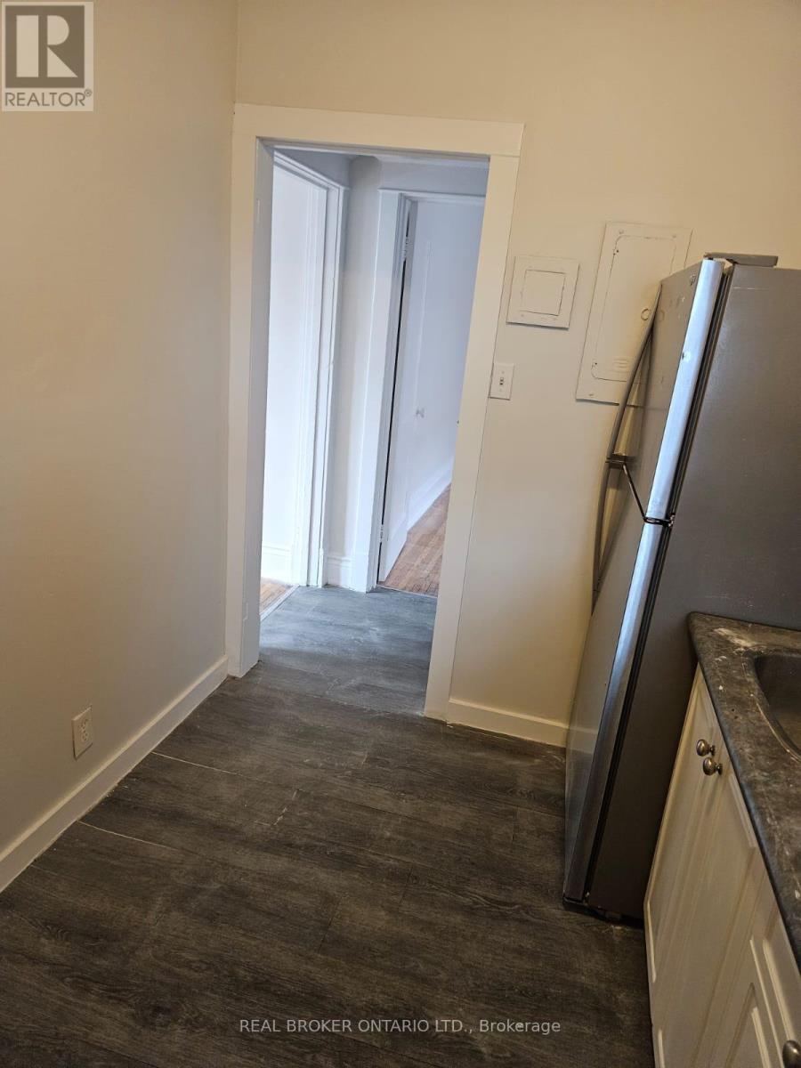 A kitchen with a refrigerator and a doorway leading to another room.