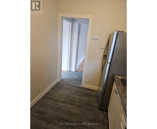 A kitchen with a refrigerator and a doorway leading to another room.