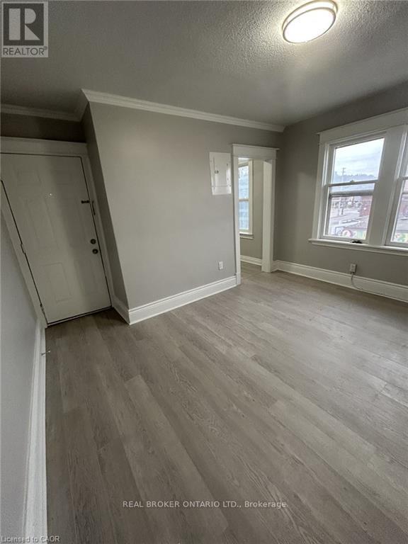 A room with wood flooring and a window overlooking a street.