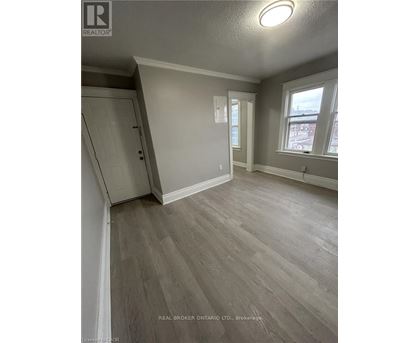 A room with wood flooring and a window overlooking a street.
