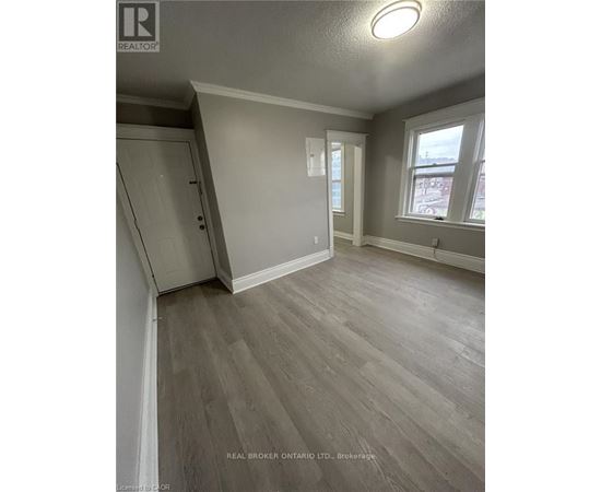 A room with wood flooring and a window overlooking a street.