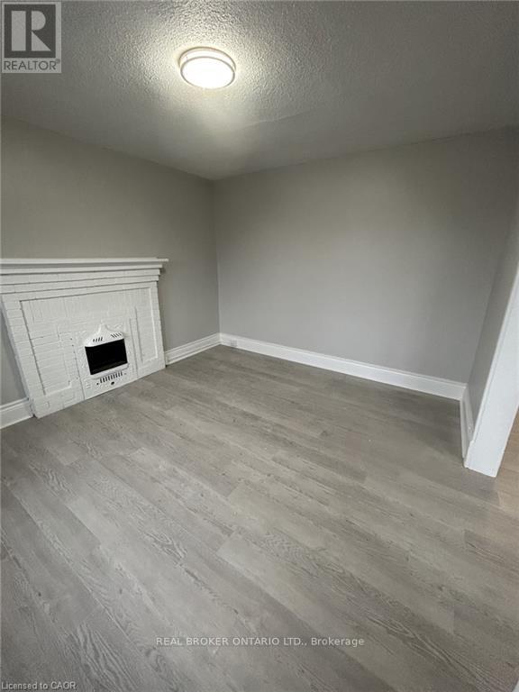 A room with a fireplace and wood flooring.
