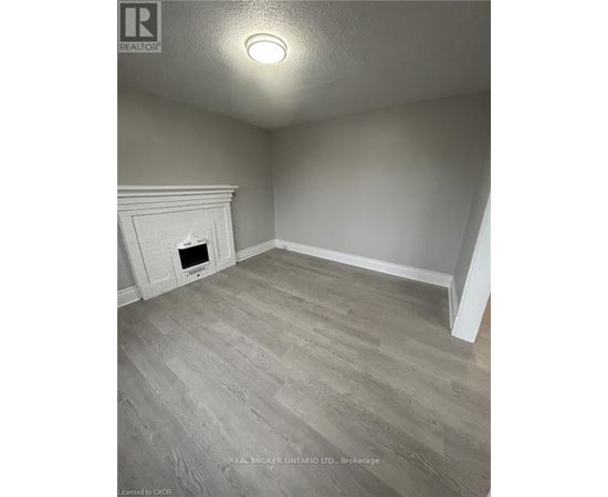 A room with a fireplace and wood flooring.