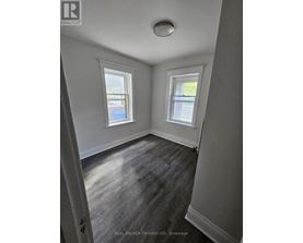 A room with two windows and a wooden floor.
