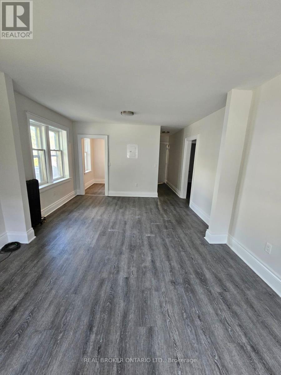 A spacious room with wood flooring and white walls.