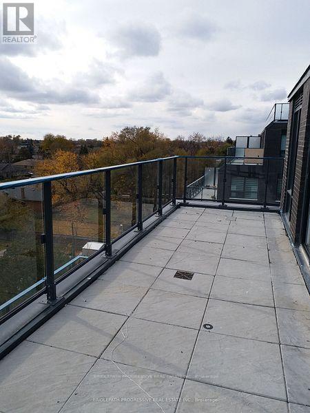 A balcony with a glass railing and a view of trees.