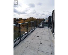 A balcony with a glass railing and a view of trees.