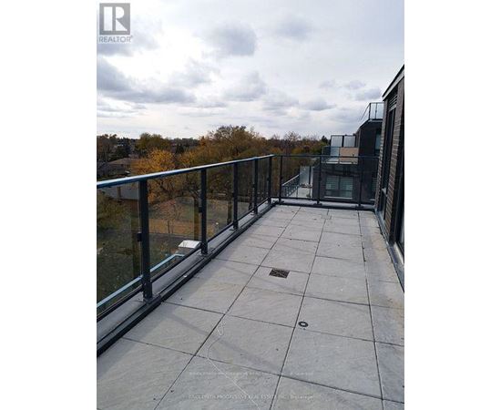 A balcony with a glass railing and a view of trees.