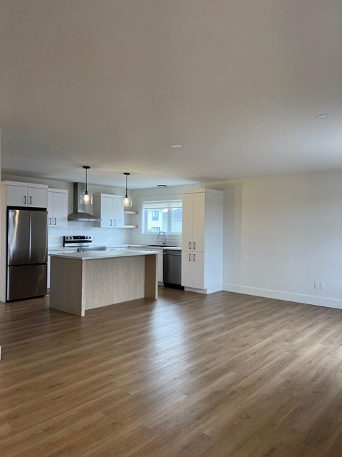 A kitchen with a refrigerator, sink, and cabinets.