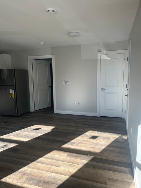 A kitchen with a refrigerator and a wooden floor.